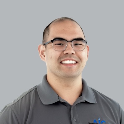 Smiling man with glasses in gray polo against light gray background